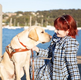A person sitting next to their yellow Labrador Guide Dog