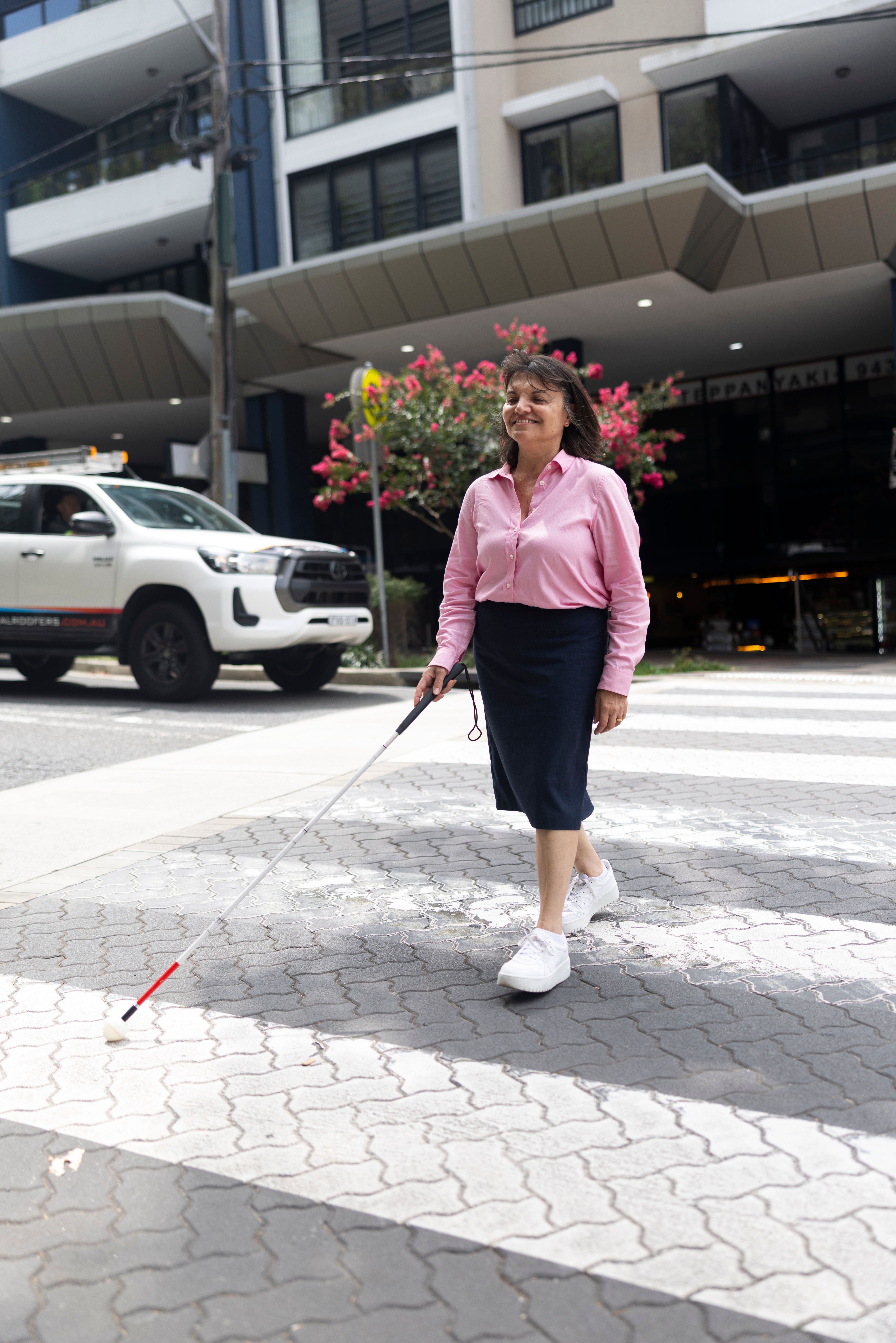 A person walking on a crossing with a cane.