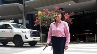 A person walking on a crossing with a cane.