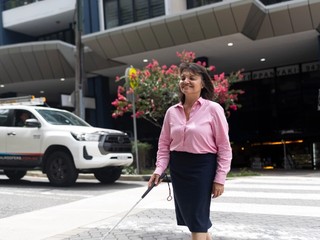 A person walking on a crossing with a cane.
