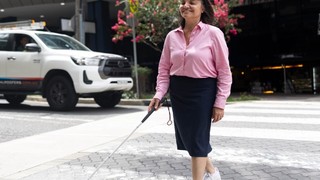 A person walking on a crossing with a cane.