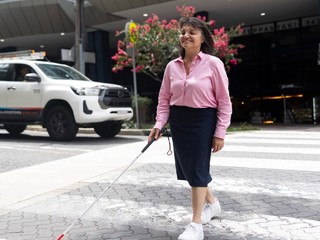 A person walking on a crossing with a cane.