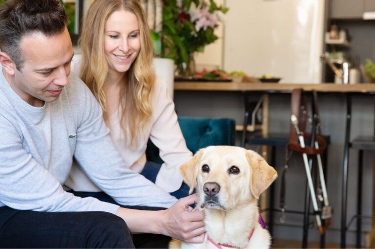 Guide Dog Poppi sitting with her Handler, Liz.