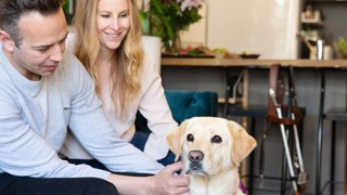 Guide Dog Poppi sitting with her Handler, Liz.