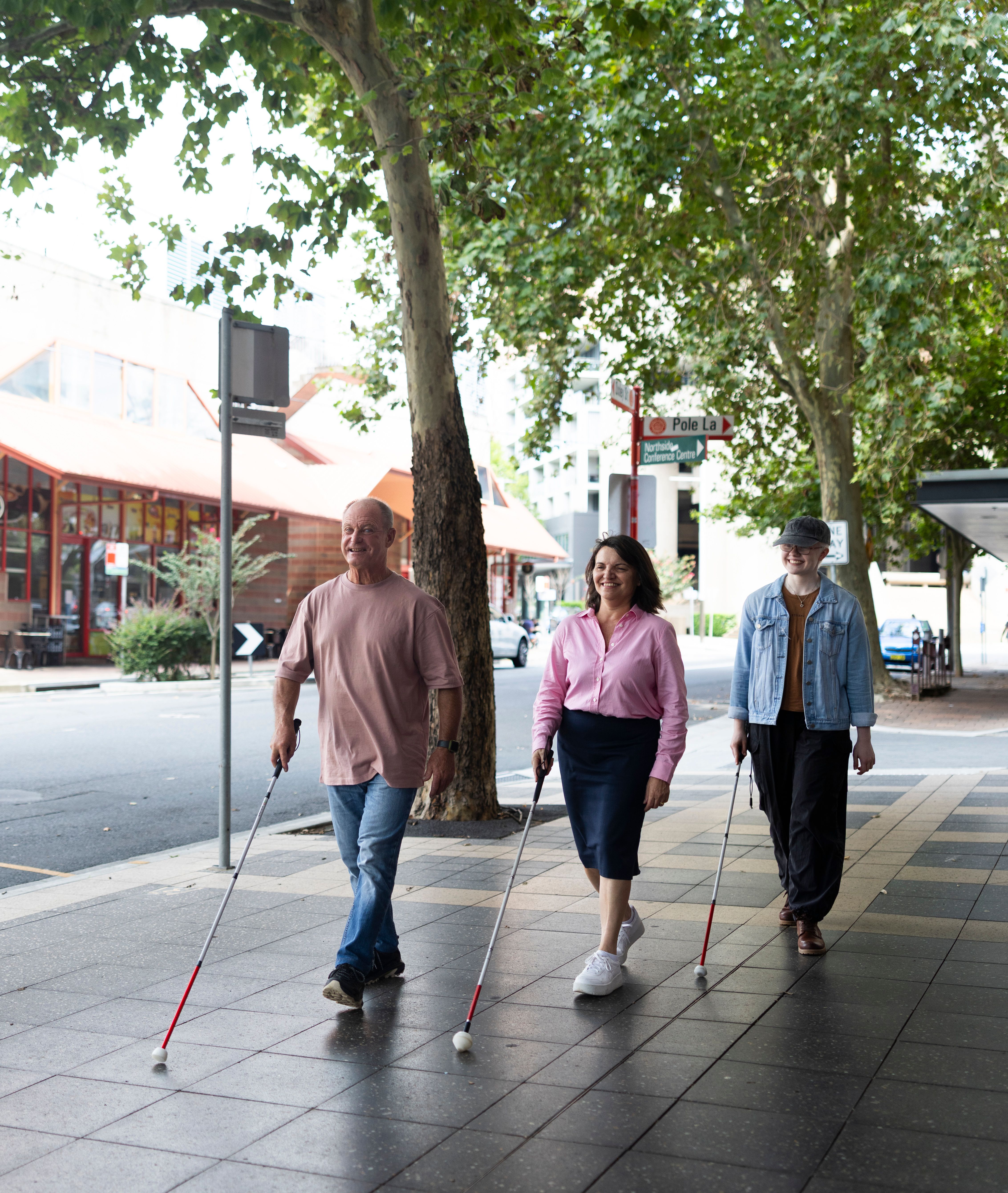 Three Guide Dog Clients walking with their canes. 