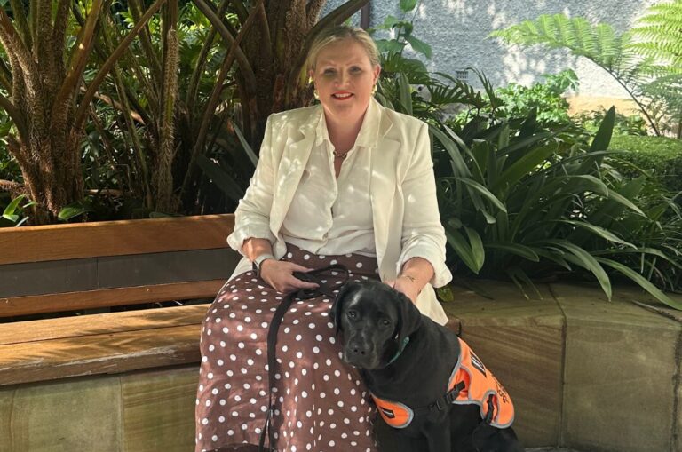 Puppy Raiser Allysia sitting with a black Labrador. 