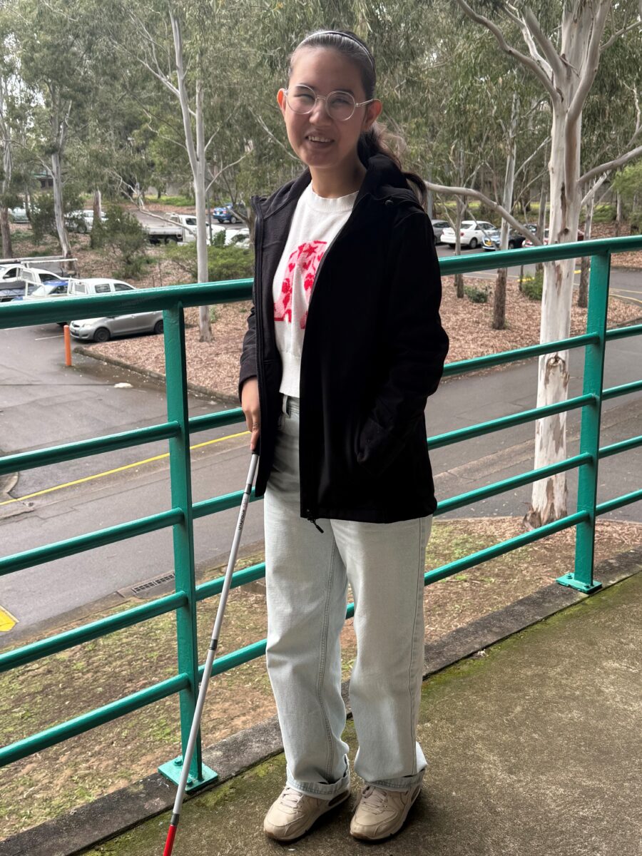 Samira standing with a white cane.