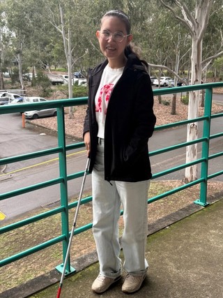 Samira standing with a white cane.