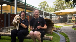 Two volunteers holding puppies.