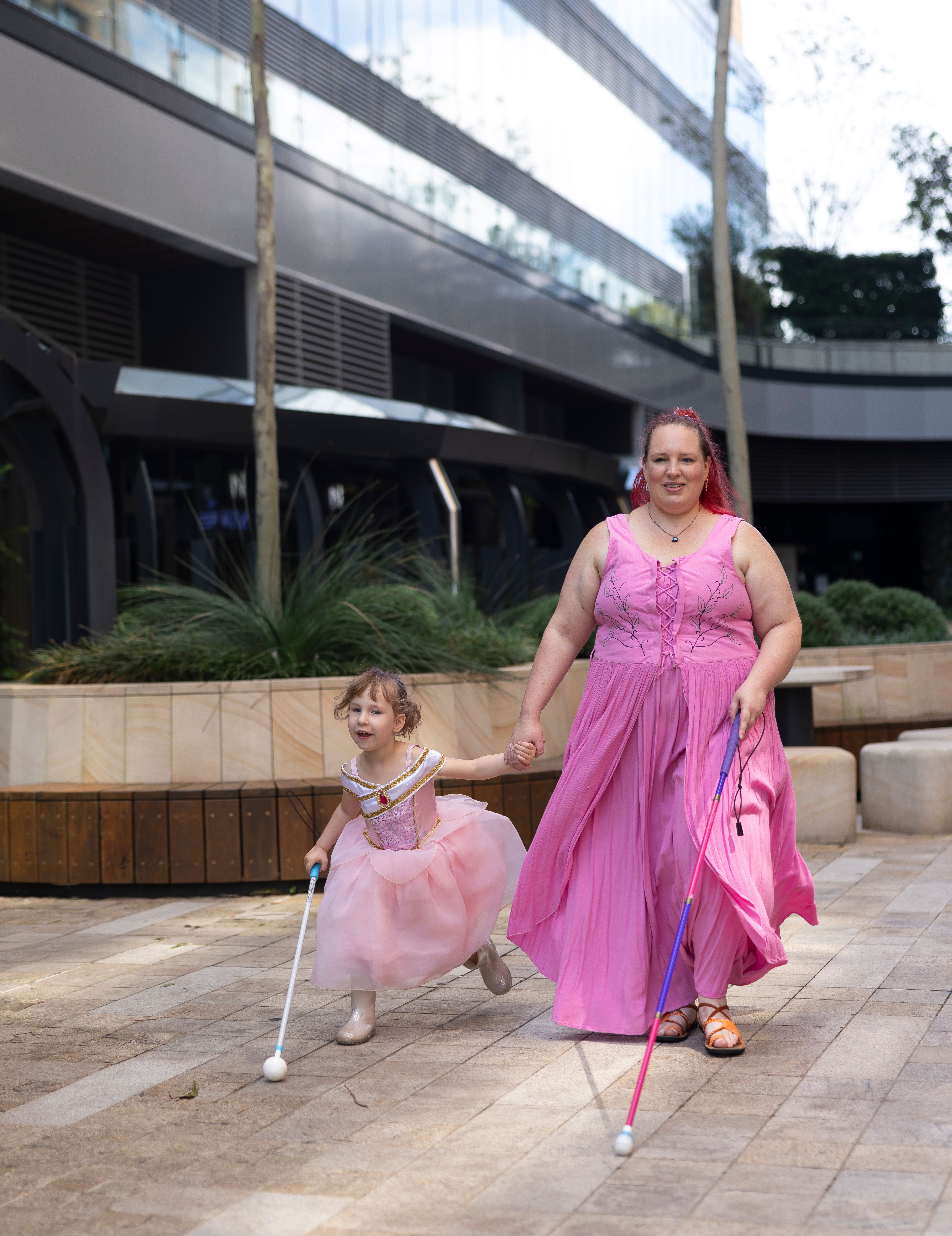 A child and their mother using white canes.