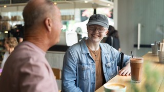 Two Clients sitting at a Cafe with each other.