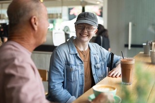 A person smiling whilst sitting at a cafe.