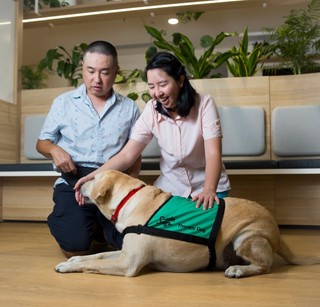 Two people petting a Therapy Dog.