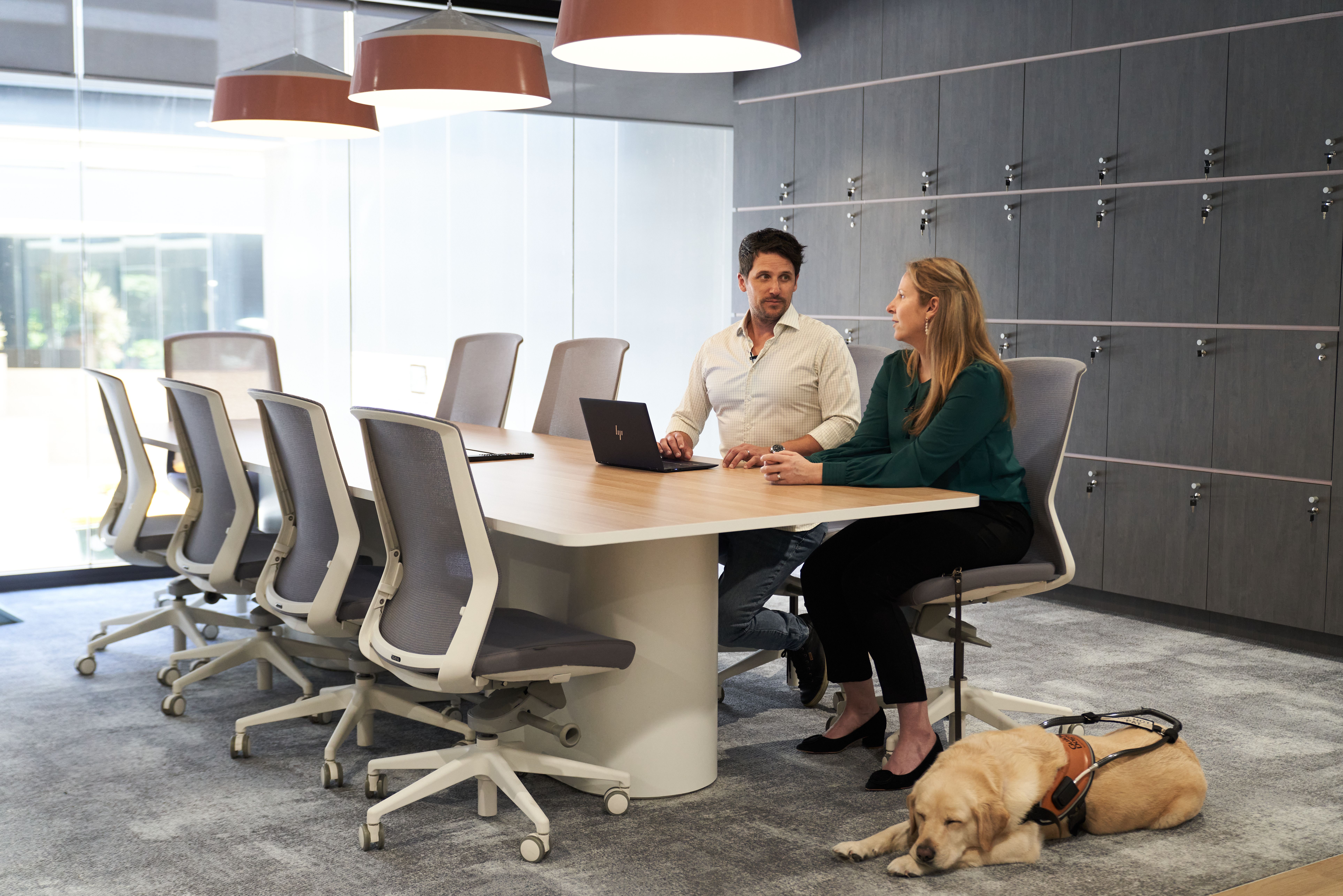 Two people sitting at a desk with a Guide Dog.