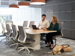 Two people sitting at a desk with a Guide Dog.