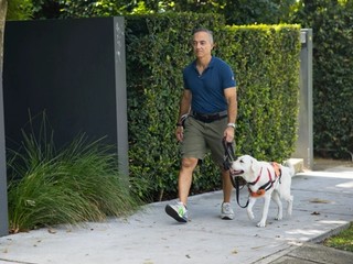 A Puppy Raiser walking with a yellow Labrador puppy.