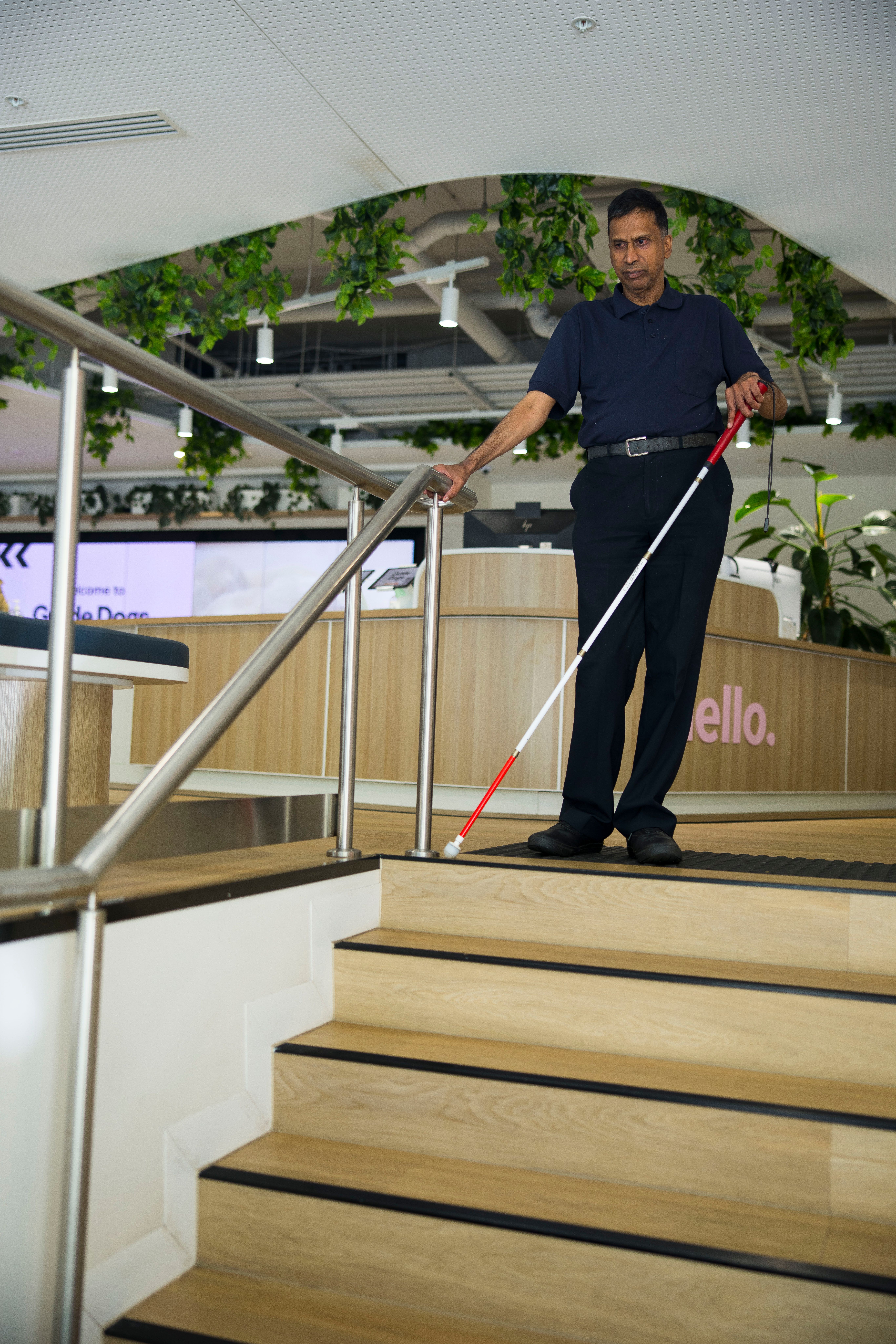 A Client walking down stairs with a cane. 