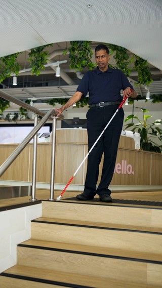 A Client walking down stairs with a cane.