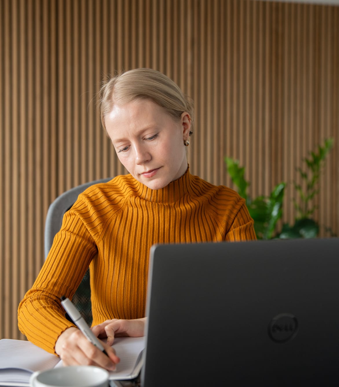 Kursist tager noter ved en bærbar computer under undervisningen