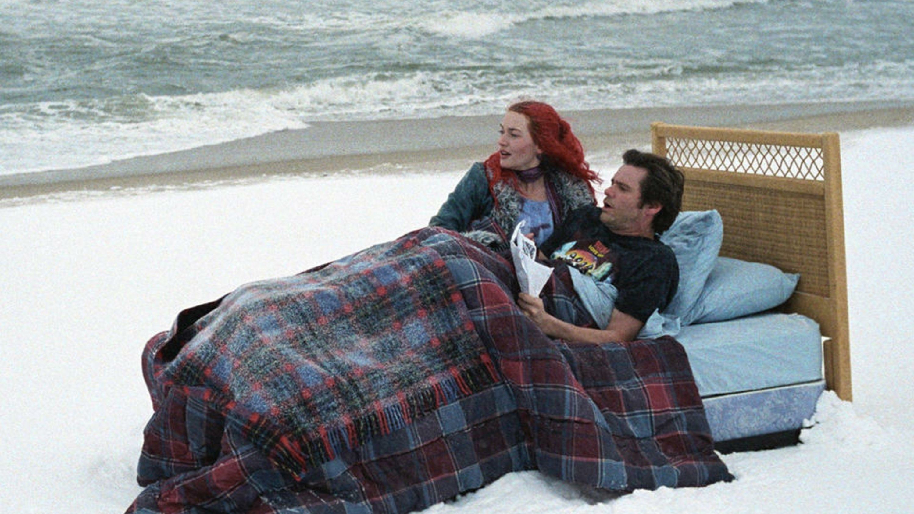 Et par ligger i en seng på en hvit strand