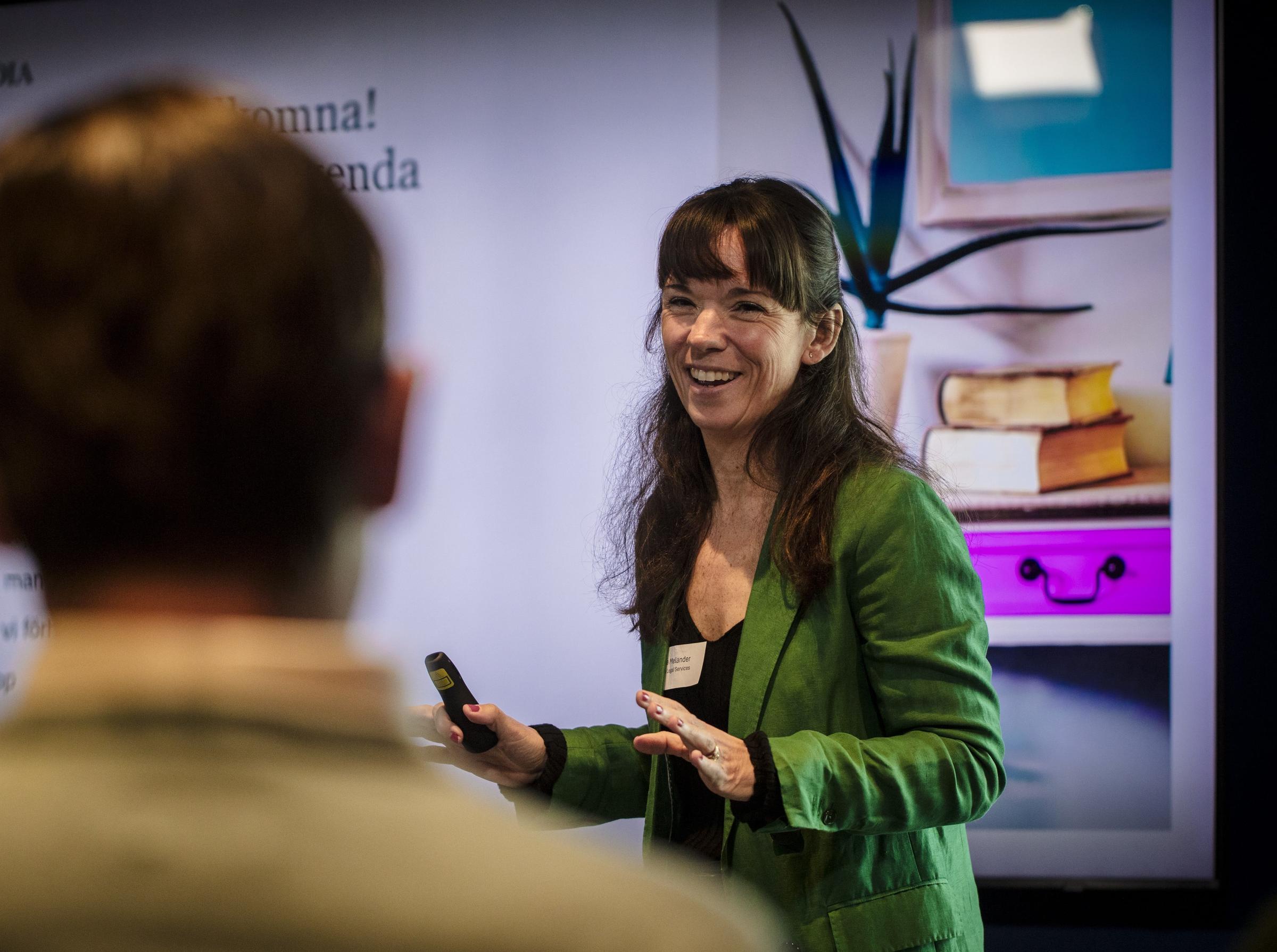 Talare Diana Melander gestikulerar med armarna samtidigt som hon ler mot publiken