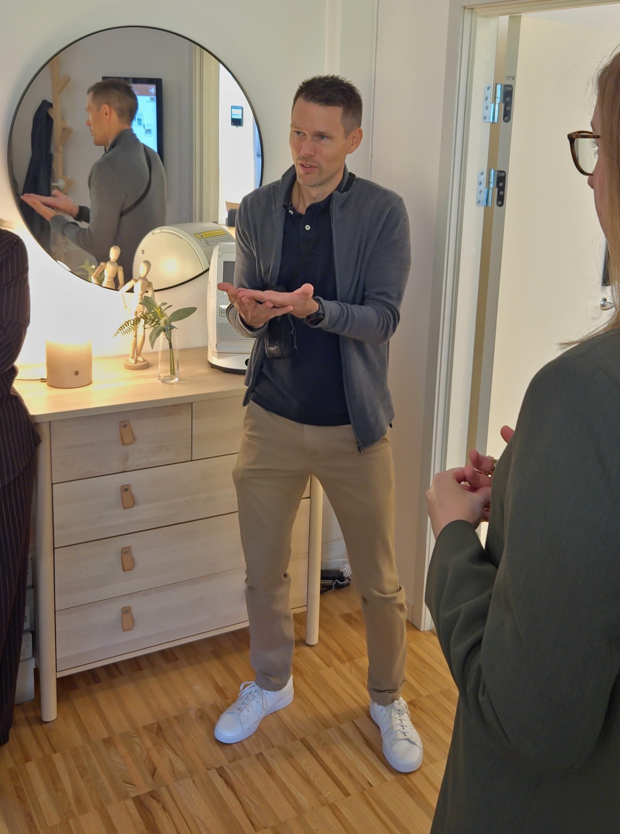 Jonas Hedin från Skaraborgs kommunalförbund står framför en byrå som har en lampa, en vas och en läkemedelsrobot placerad på sig