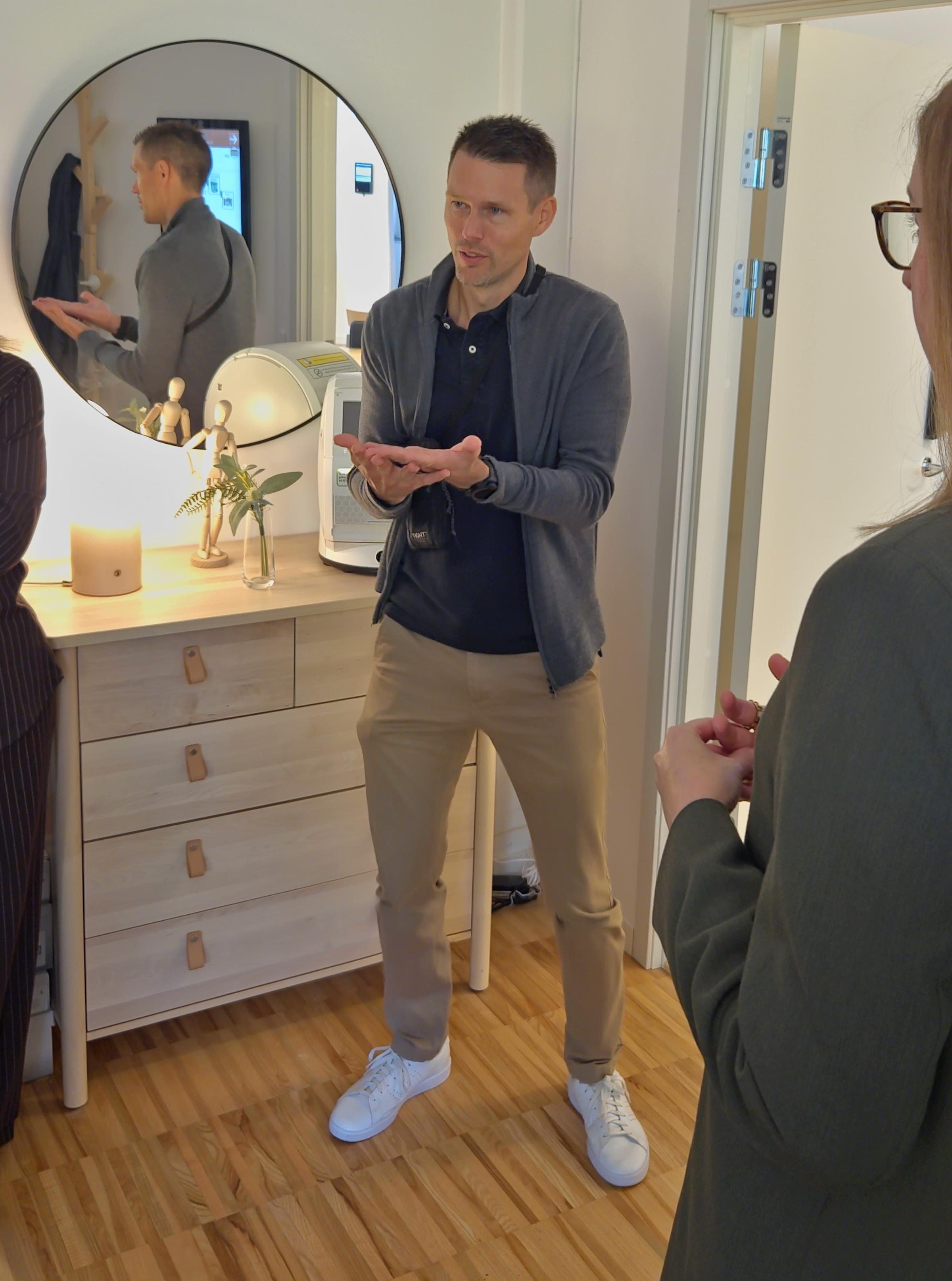 Jonas Hedin från Skaraborgs kommunalförbund står framför en byrå som har en lampa, en vas och en läkemedelsrobot placerad på sig