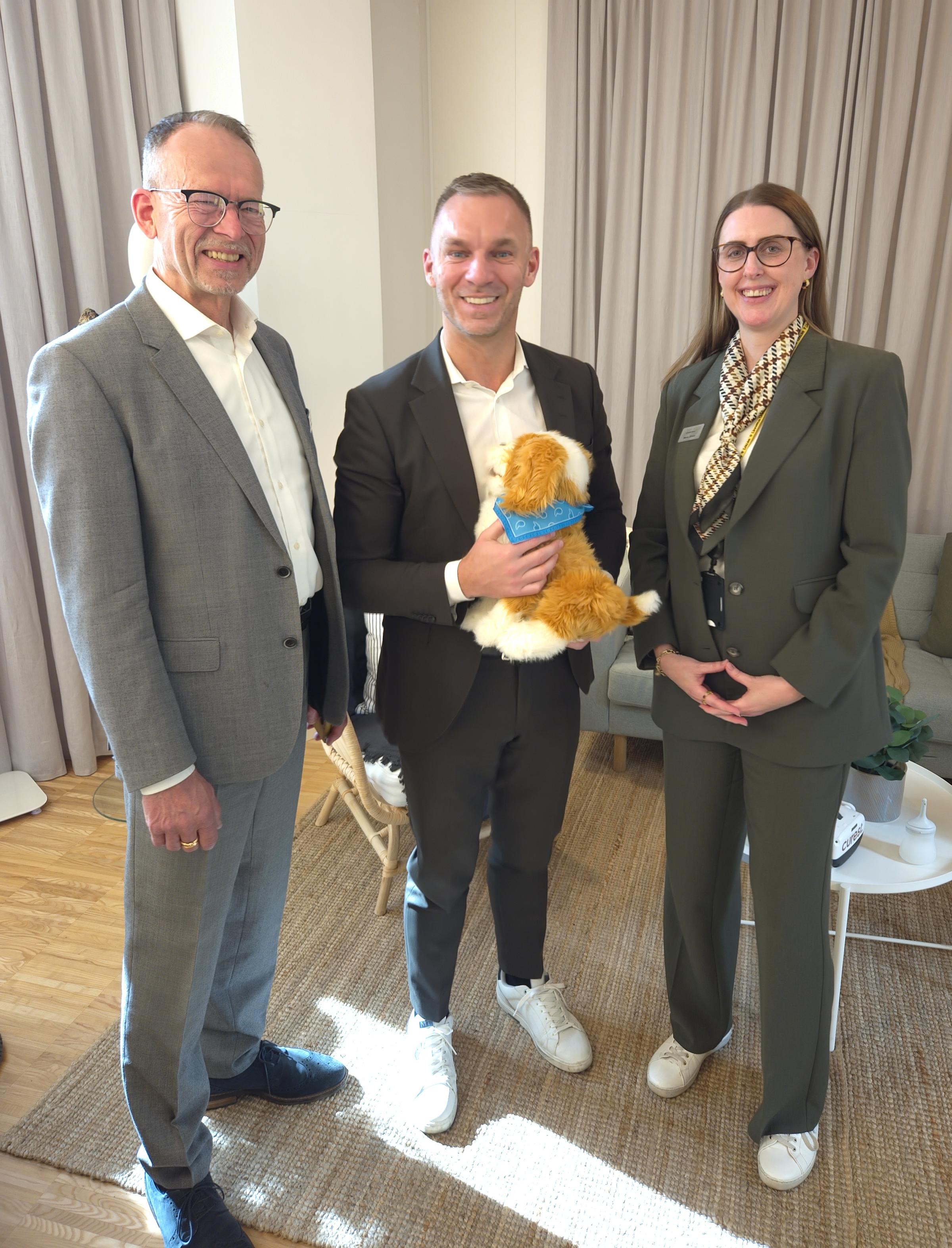 Civilminister Erik Slottner med robothund i famnen, bredvid står personal från eHealth Arena.
