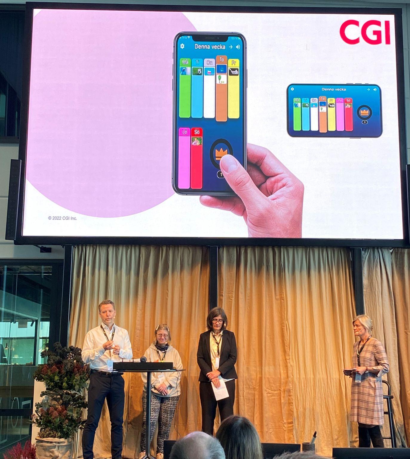 Bild på representanter från CGI som står på en scen och pratar till en powerpoint-bild som visar "Glada schemat".