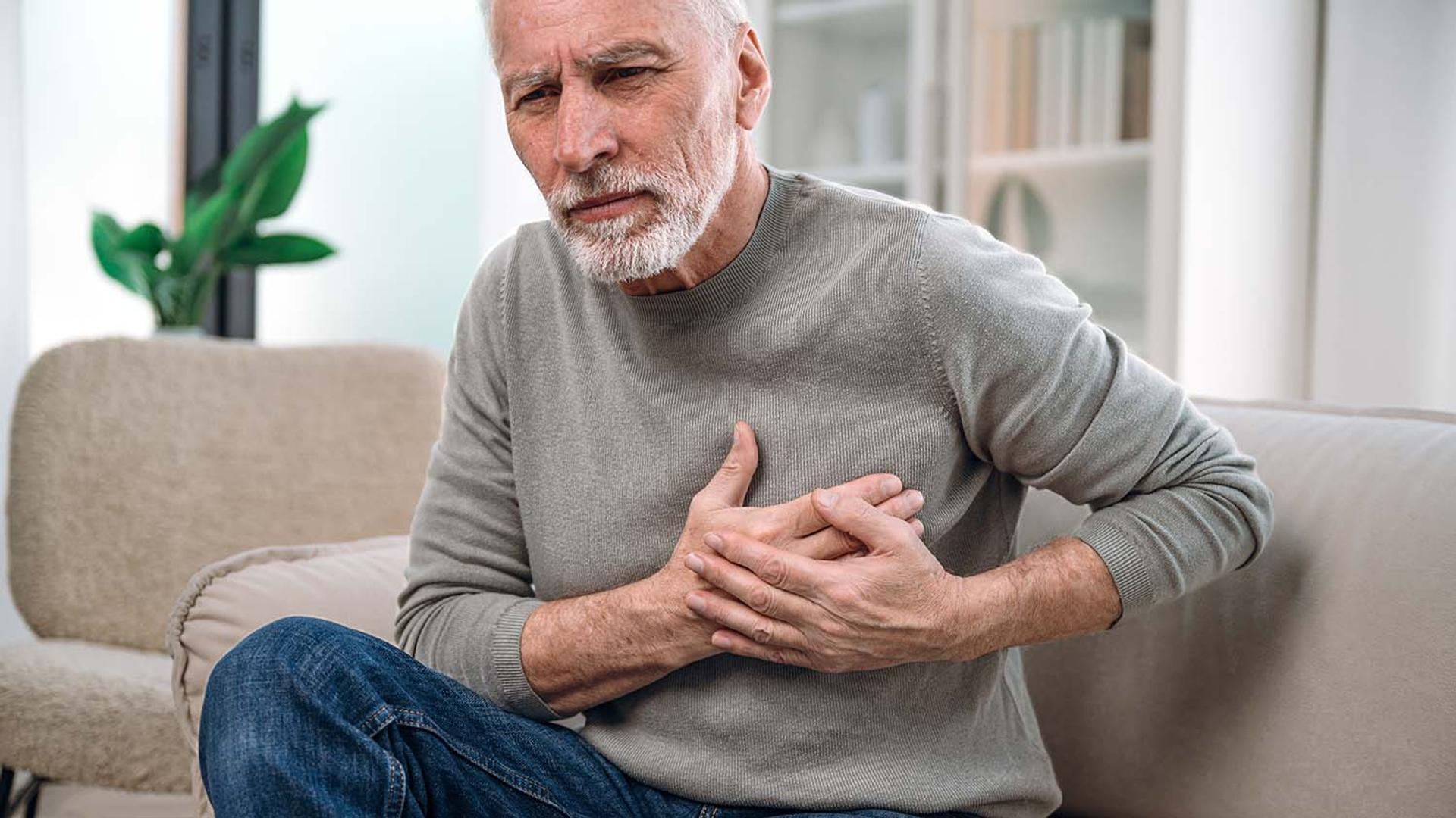 Senior man with a pained expression clutching his chest.
