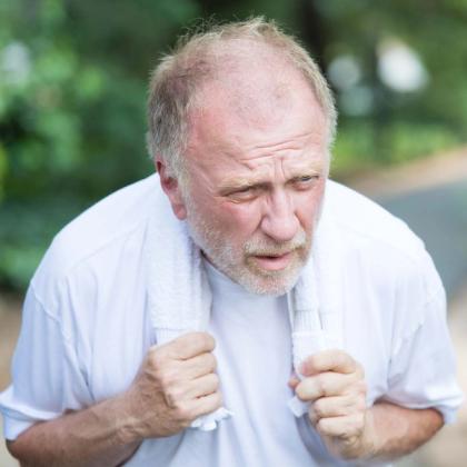 Senior man looking exhausted with a towel around his neck outdoors