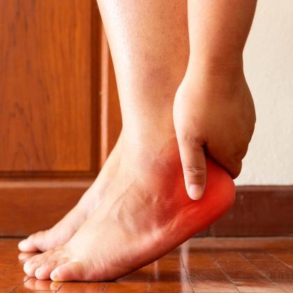 Person holding their painful, red heel.