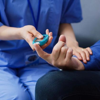 Healthcare professional using a pulse oximeter on a patient's finger to measure oxygen saturation levels