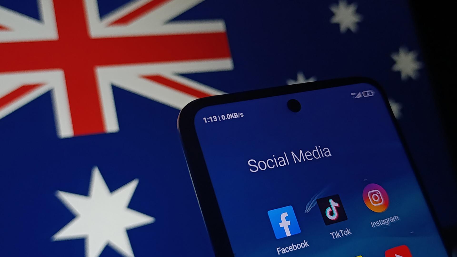 A smartphone screen shows social media apps over a blurred Australian flag.