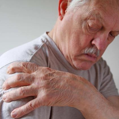 Elderly man touching his shoulder in pain, depicting signs of arthritis or discomfort