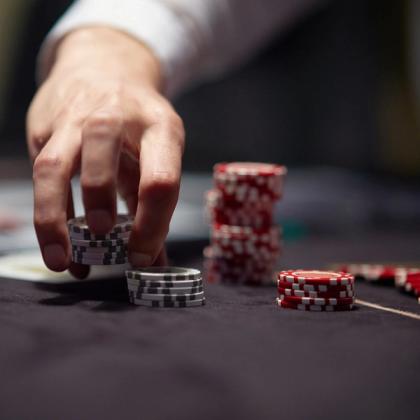Close-up of a person's hand placing poker chips on a gaming table, with focus on the chips and hand.