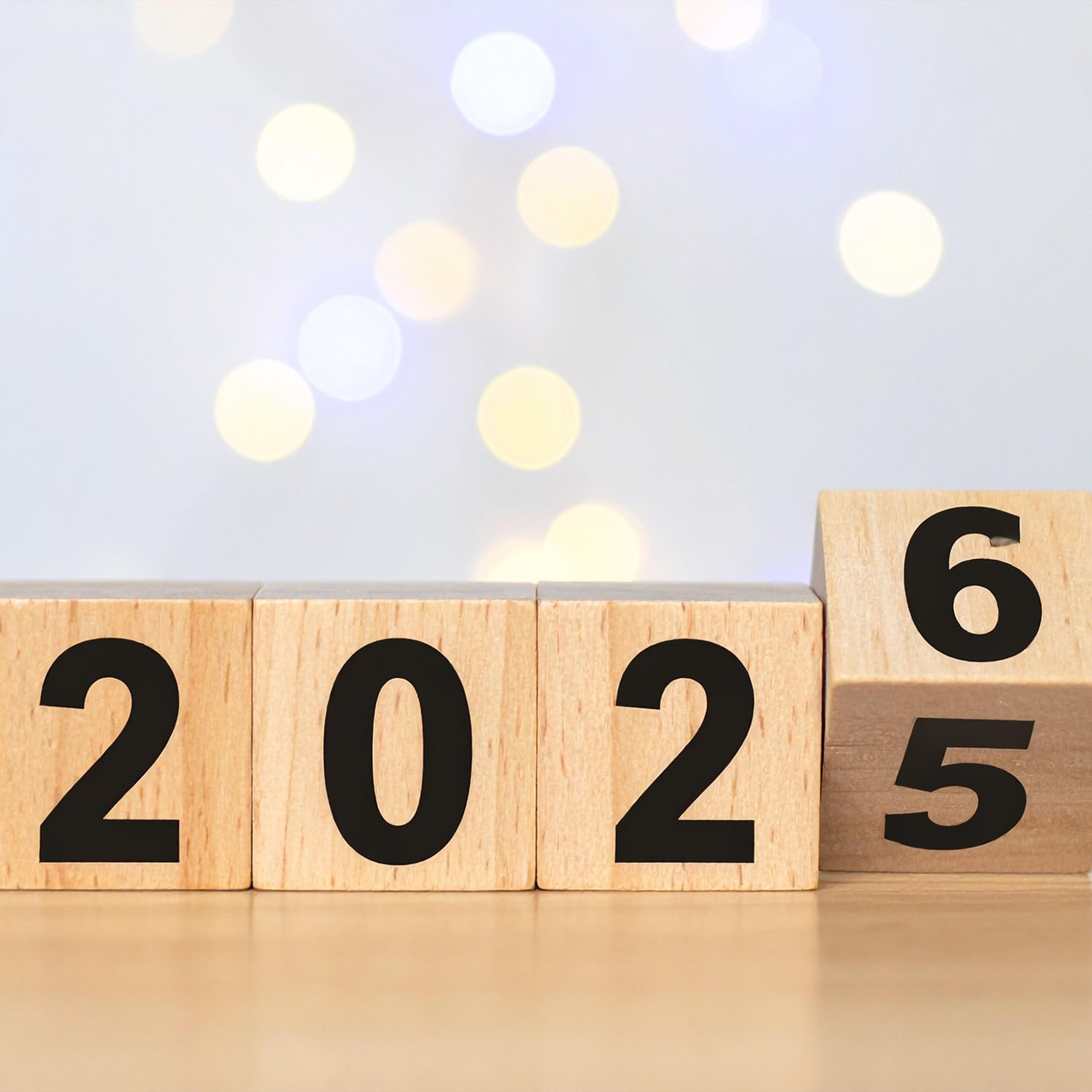 Wooden blocks show the year changing from 2025 to 2026.