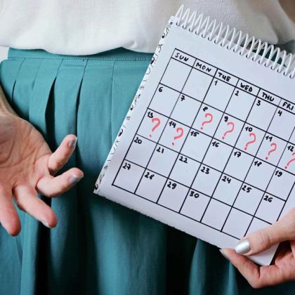 Person holding a calendar with question marks on specific dates, indicating uncertainty or scheduling conflicts.