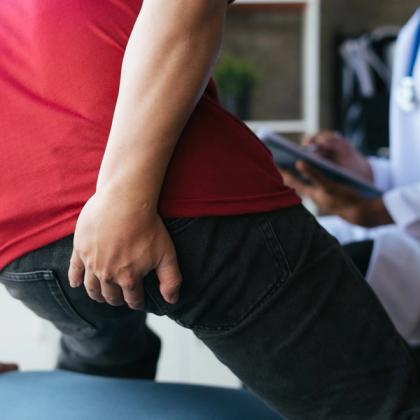 Patient with lower back pain receiving consultation from a doctor in the background