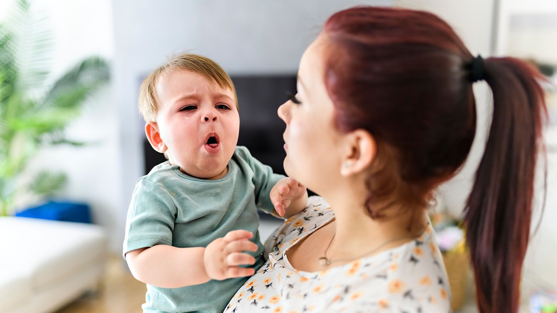 A woman holds a crying baby.