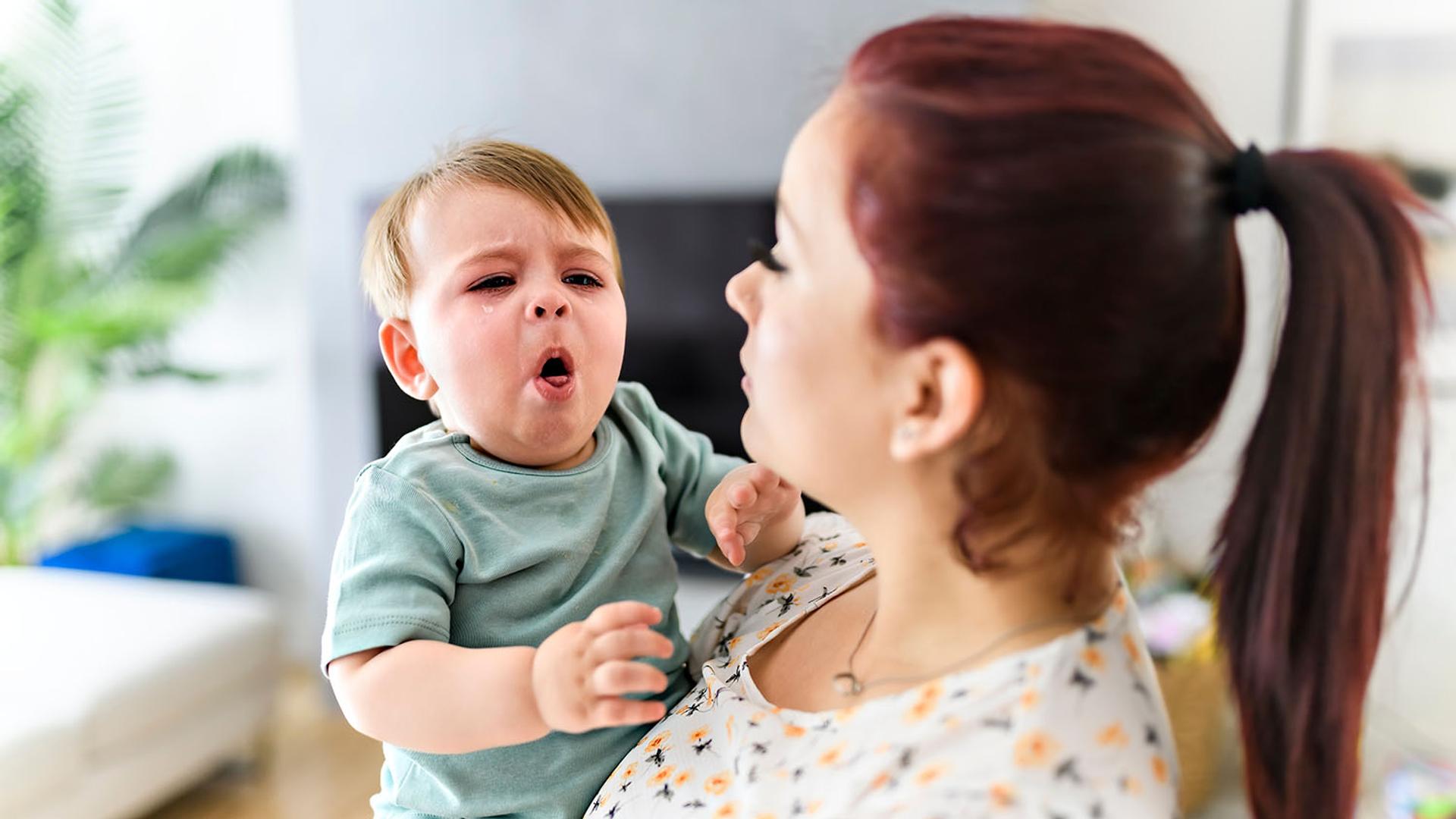 A woman holds a crying baby.