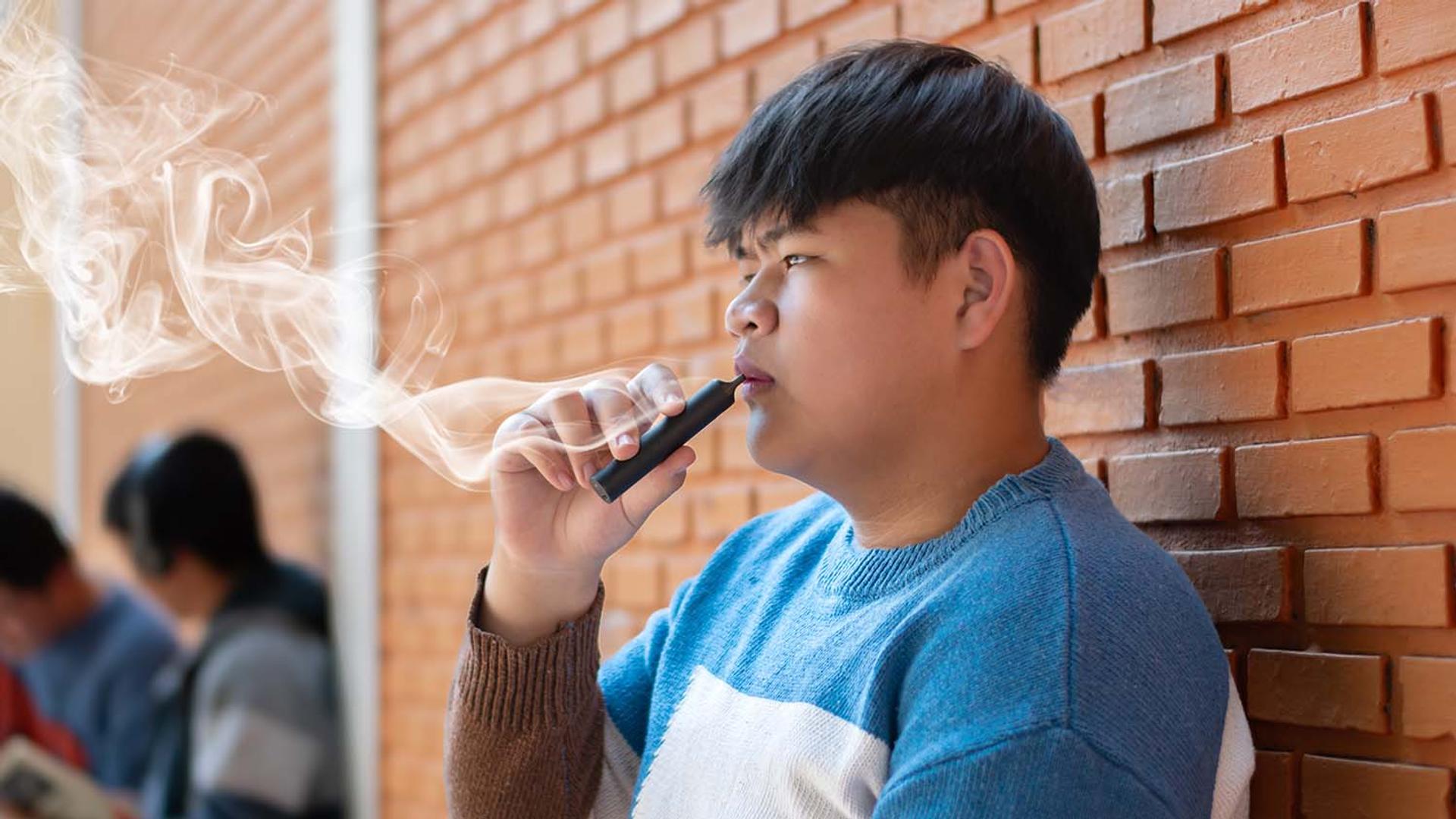 A teenage boy exhaling vapor from a vape device.