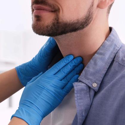 Doctor in blue gloves examining male patient's thyroid gland or lymph nodes