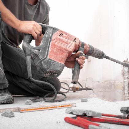 Worker using a heavy-duty drill for construction work on a concrete floor