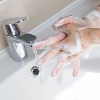 Person washing hands with soap under running water from a modern faucet