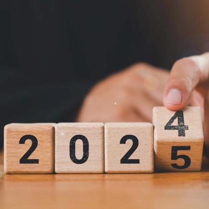 Person changing the year from 2024 to 2025 using wooden blocks, symbolizing the new year transition.