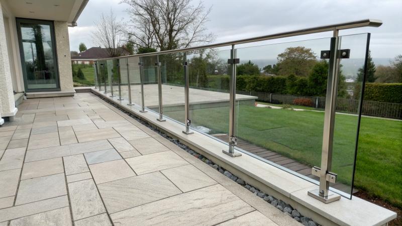 Stainless steel base shoe channel holding frameless glass railing panels on a stone patio