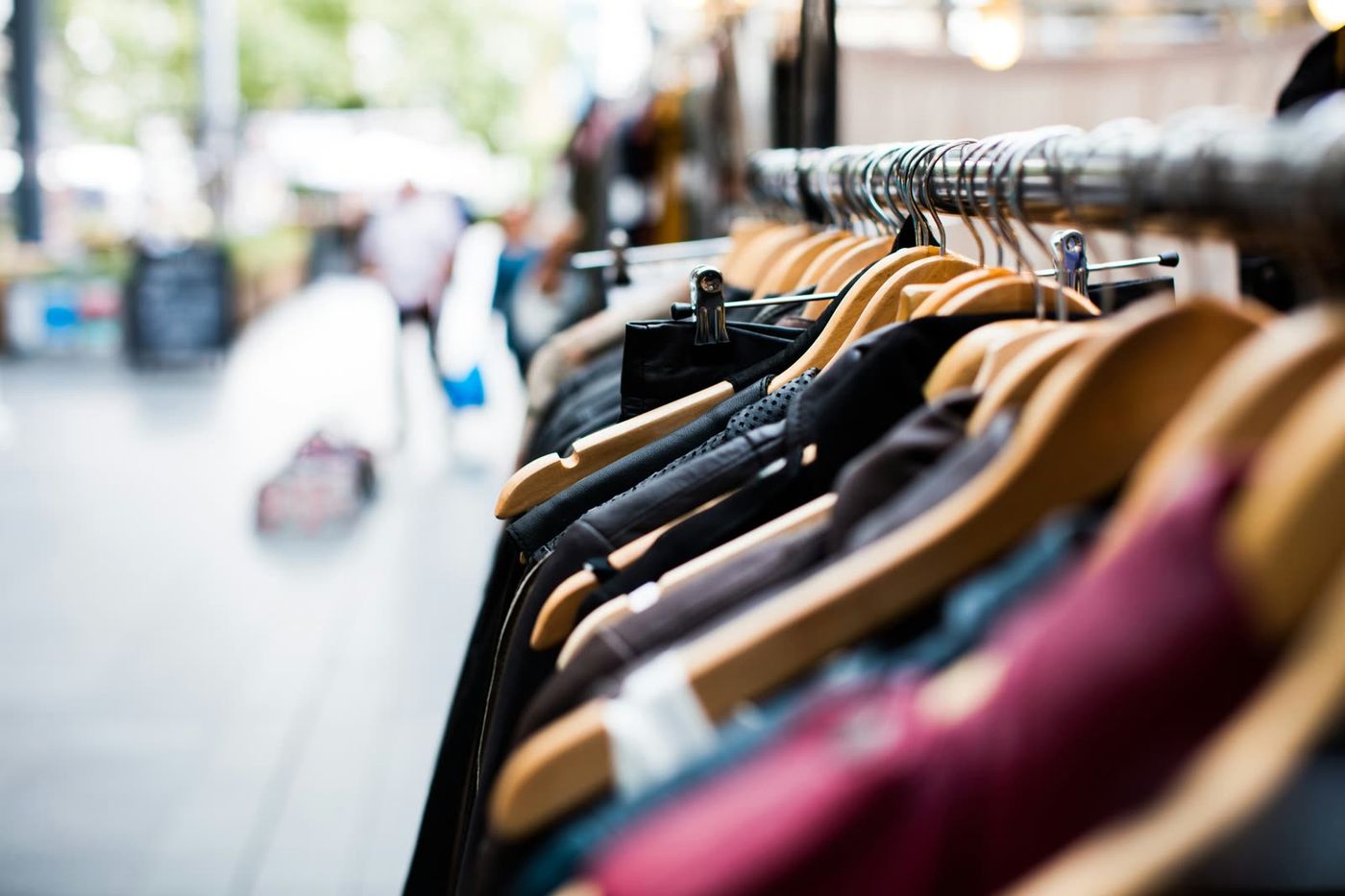 Kleding aan een kledingrek met de winkelstraat op de achtergrond