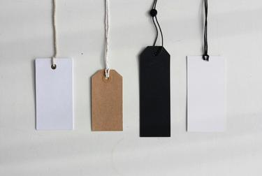 Four paper tags of different colors with strings attached on a plain white background