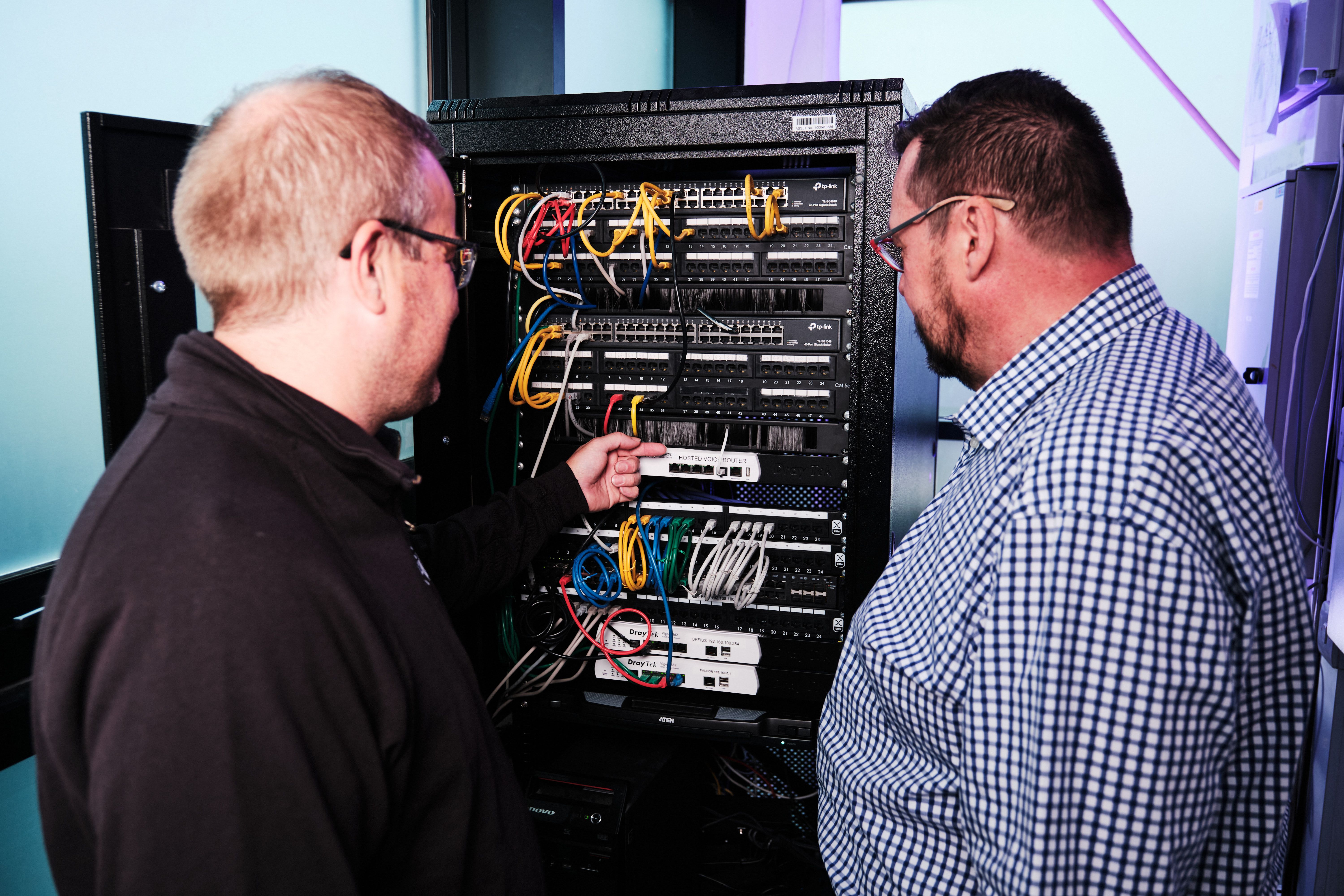 An IT engineer inspecting a server cabinet, illustrating what gets discovered when onboarding a client from another IT supplier